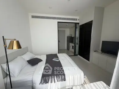 Modern bedroom with cozy bed, stylish lamp, and sleek TV setup in a contemporary apartment.