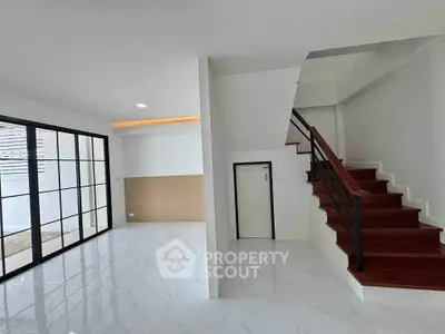 Modern interior with sleek staircase and large windows in a bright living space.