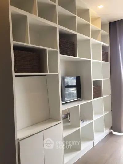 Modern living room with stylish built-in shelving and city view window.