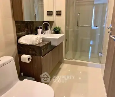Modern bathroom with glass shower and sleek vanity in luxury apartment.