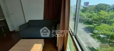 Cozy living room with large window offering lush green view, perfect for relaxation.