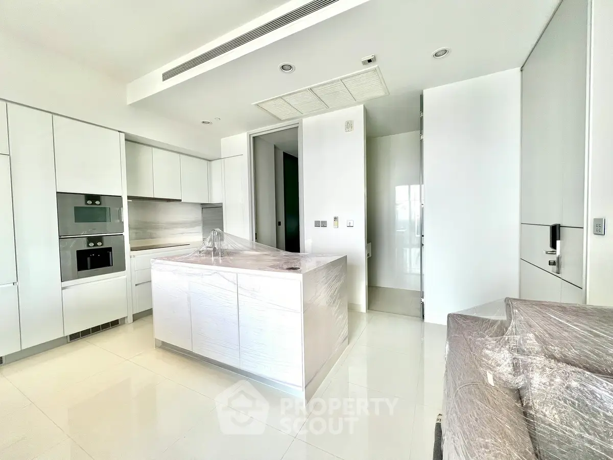 Modern kitchen with sleek white cabinetry and central island in luxury apartment