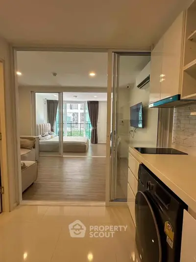 Modern apartment interior with open kitchen and cozy living area, featuring sleek appliances and stylish decor.