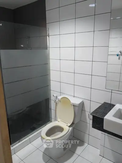 Modern bathroom with glass shower and tiled walls in a real estate property.