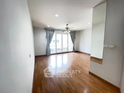 Spacious empty living room with hardwood floors and large windows for natural light.