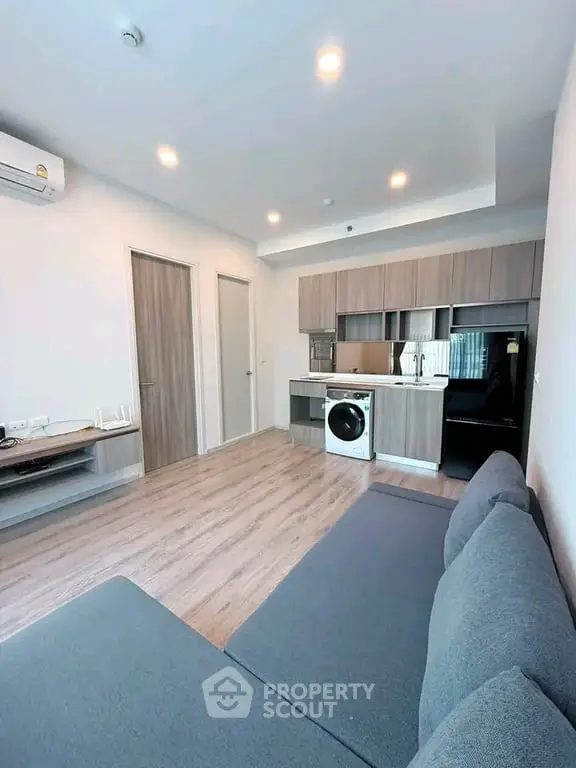 Modern living room with open kitchen and washing machine in stylish apartment.