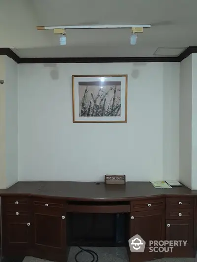 Spacious study area with elegant wooden desk and framed artwork, ideal for home office setup.