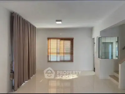 Spacious empty living room with large window and modern tile flooring, perfect for customization.