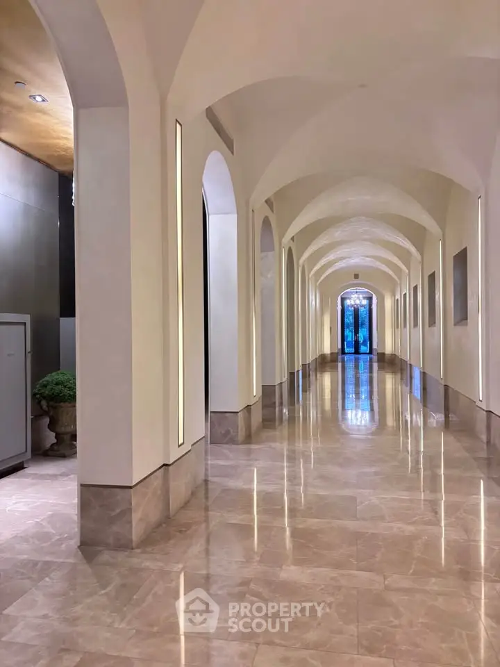 Elegant hallway with arched ceilings and polished marble floors in luxury building.