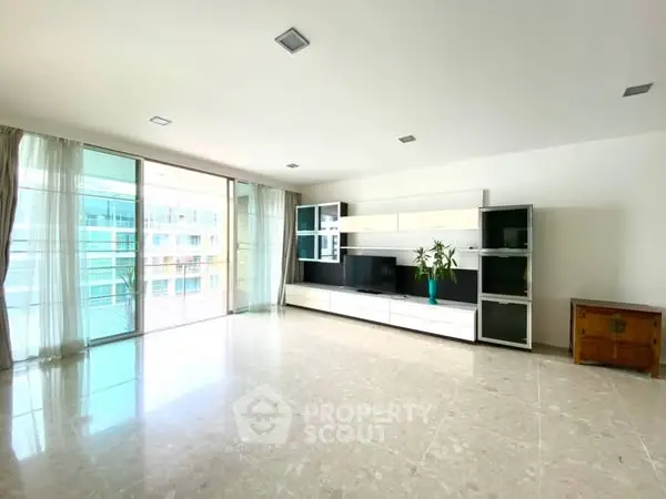 Spacious modern living room with large windows and sleek entertainment unit.