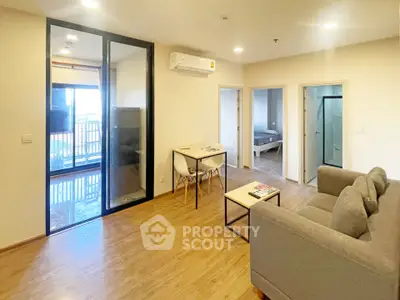 Modern living room with wooden flooring, cozy sofa, and dining area in open layout apartment.