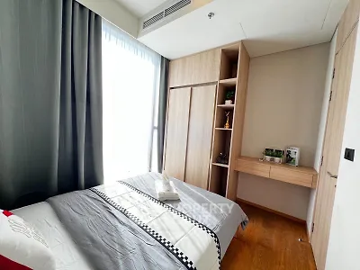 Modern bedroom with natural light, wooden flooring, and built-in wardrobe in a stylish apartment.