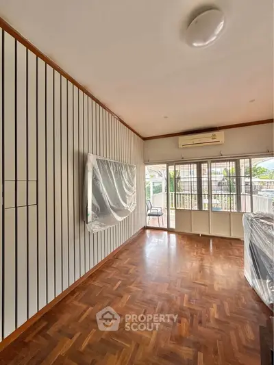 Spacious living room with parquet flooring and large windows for natural light.