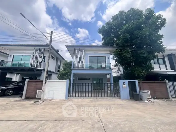 Modern two-story house with sleek design and spacious driveway in a suburban neighborhood.
