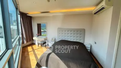 Spacious bedroom with large windows and city view, featuring modern decor and ample natural light.