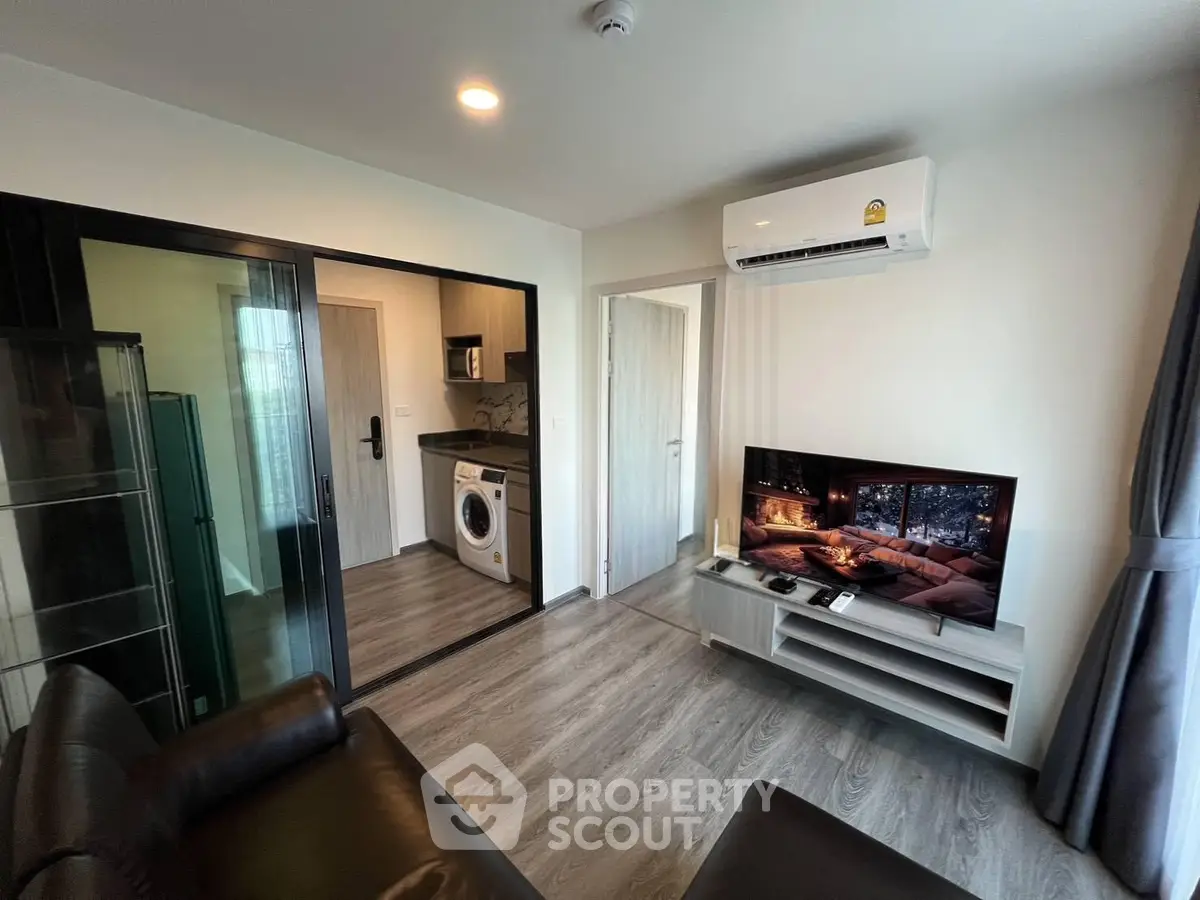Modern living room with sleek furniture and integrated kitchen featuring a washing machine, perfect for urban living.