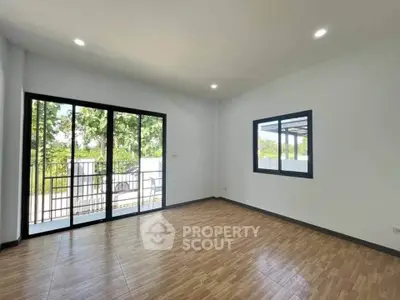 Spacious living room with large windows and wooden flooring, offering a bright and airy atmosphere.