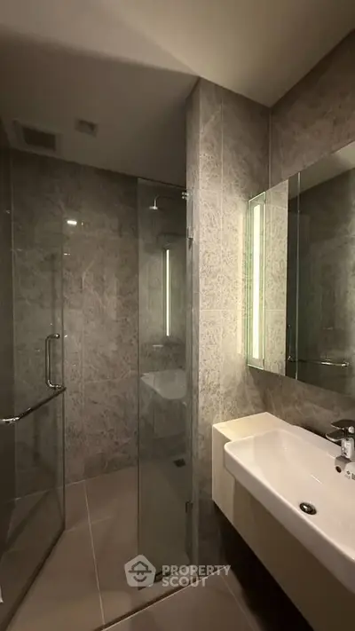 Modern bathroom with sleek glass shower and elegant sink in luxury apartment.