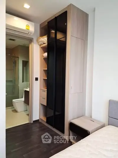 Modern bedroom with built-in wardrobe and en-suite bathroom in stylish apartment.