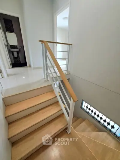 Modern staircase with wooden steps and sleek railing in a bright home interior