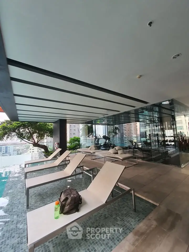 Luxurious rooftop pool area with modern lounge chairs and stunning city views, perfect for relaxation and leisure.
