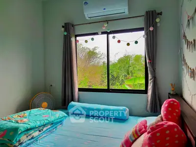 Cozy bedroom with vibrant blue flooring, large window offering lush green views, and playful decor, perfect for a restful retreat.