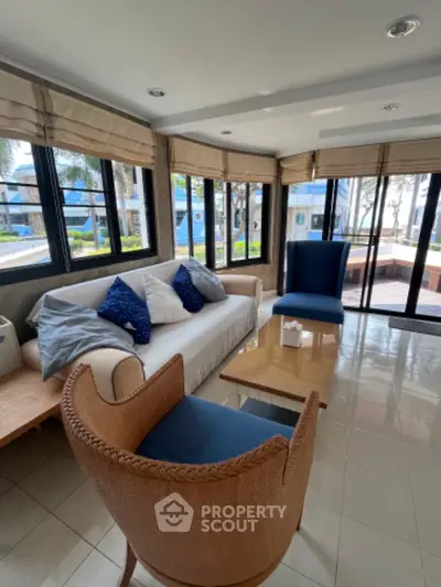 Bright living room with modern furniture and large windows offering garden views