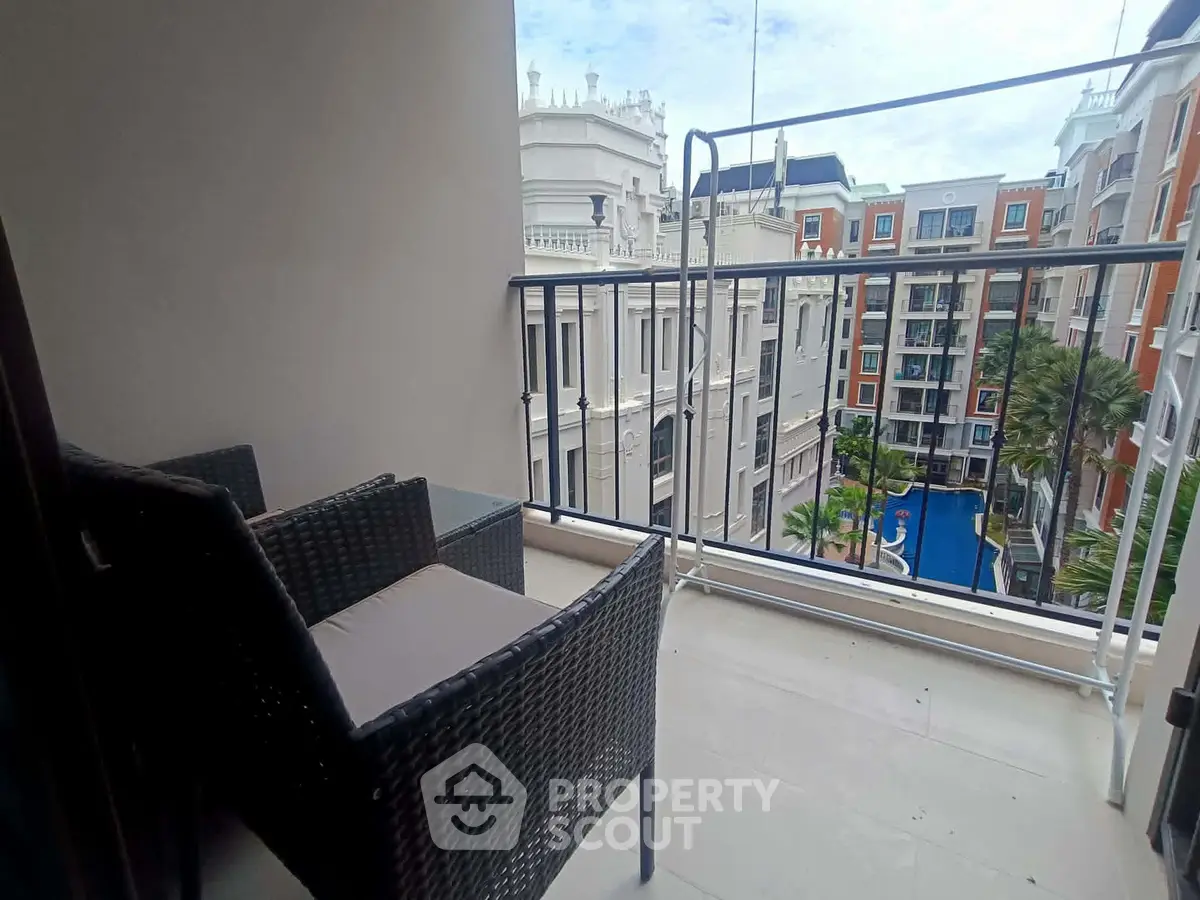 Charming balcony with cozy seating and stunning cityscape view in modern apartment complex.