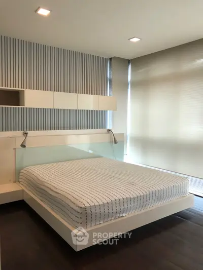 Modern bedroom with sleek design, featuring a stylish bed and floor-to-ceiling windows for natural light.