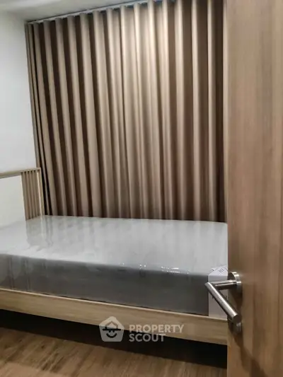 Cozy bedroom with modern design and wooden flooring, featuring a comfortable bed and elegant curtains.