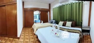 Spacious bedroom with elegant decor and twin beds, featuring wooden flooring and green curtains.