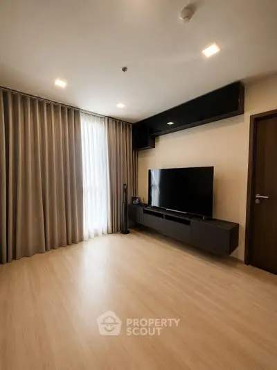 Spacious modern living room with sleek TV setup and elegant curtains
