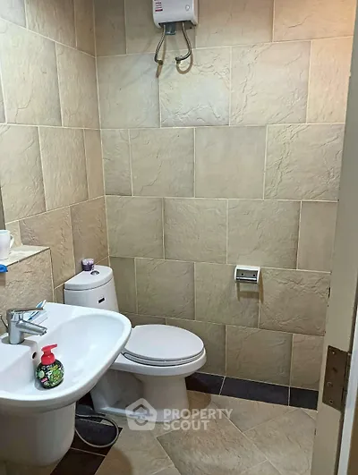 Compact bathroom with modern fixtures and tiled walls, featuring a toilet and sink.