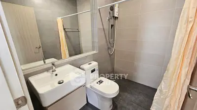 Modern bathroom with sleek fixtures and neutral tiles, featuring a shower and vanity.