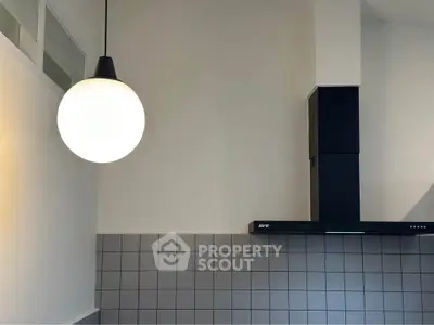 Modern kitchen with sleek black range hood and stylish pendant light.