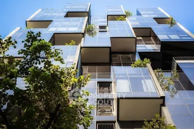 Modern architectural building with glass facade and greenery, showcasing contemporary urban living.