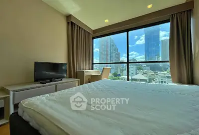 Spacious bedroom with large window offering stunning city views, modern furnishings, and natural light.