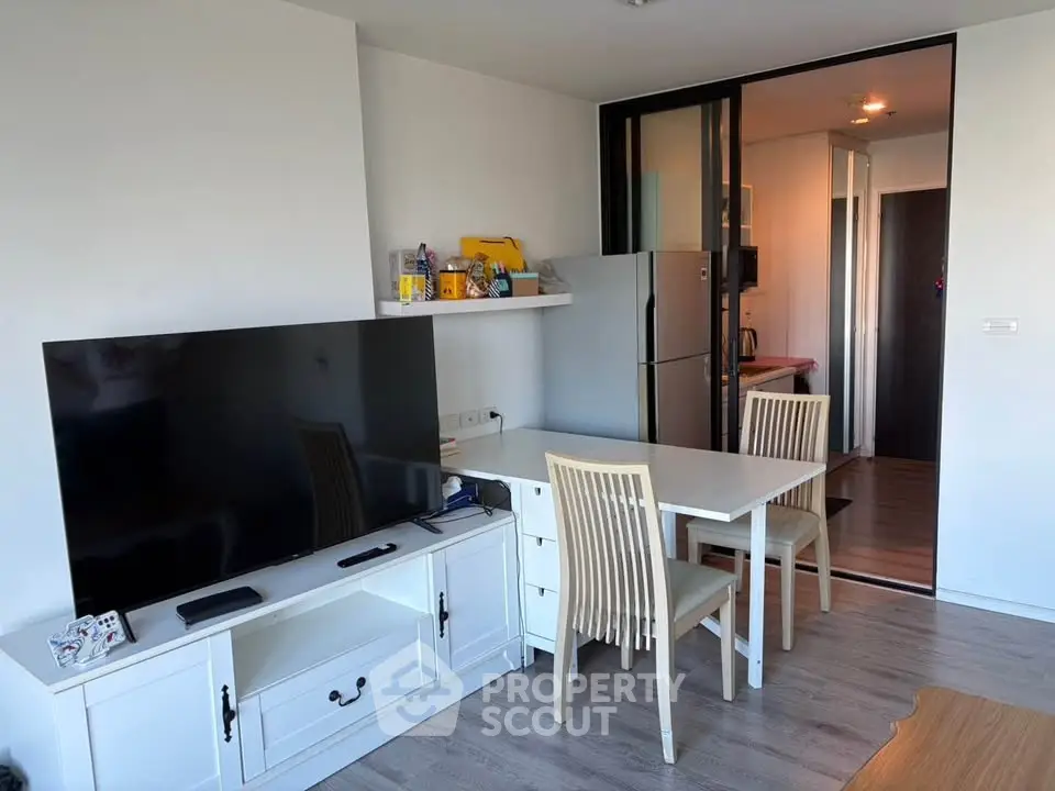Modern living room with dining area and large TV, featuring sleek furniture and open layout.