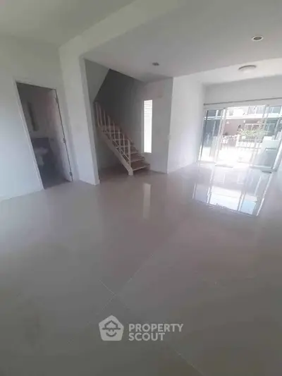 Spacious modern living room with glossy tile flooring and staircase