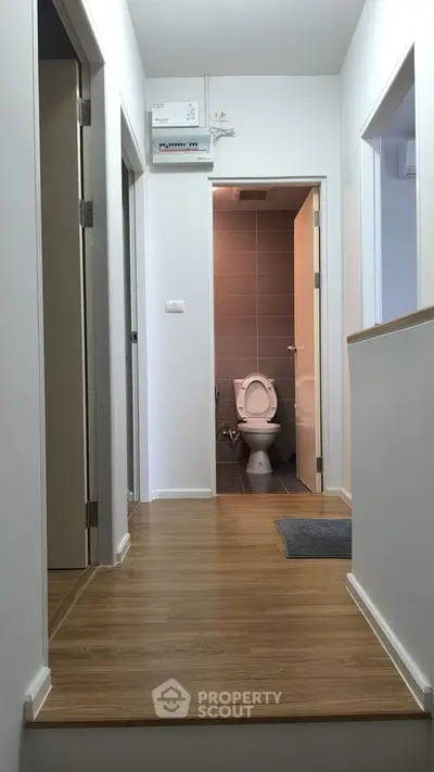 Modern hallway leading to a bathroom with sleek design and wooden flooring