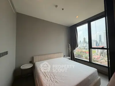 Modern bedroom with large windows offering stunning city views in a high-rise apartment.