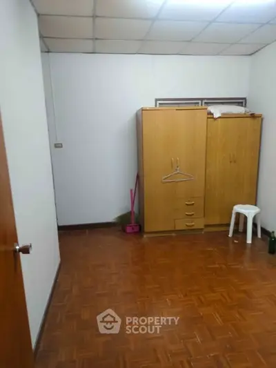 Simple bedroom with wooden wardrobe and parquet flooring, ideal for minimalist living.