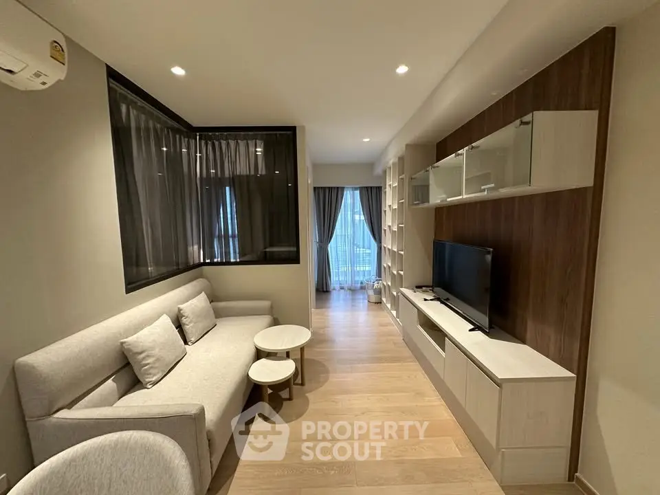 Modern living room with sleek furniture and large window offering natural light.