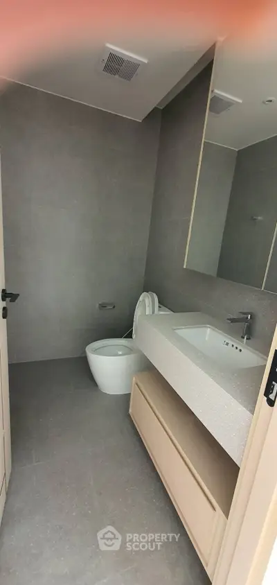 Modern bathroom with sleek design and spacious layout, featuring a large mirror and contemporary fixtures.