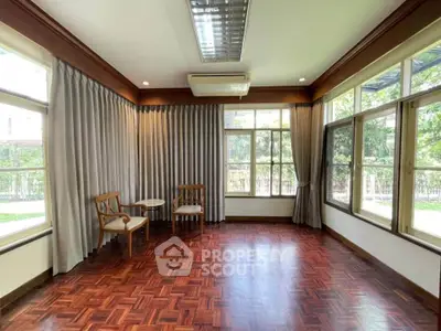 Spacious room with parquet flooring and large windows offering garden views.