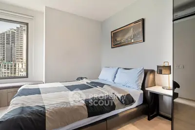 Modern bedroom with stylish decor and city view, featuring a comfortable bed and elegant lighting.