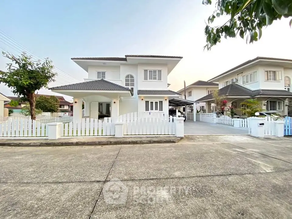 Charming two-story white house with a picket fence and spacious driveway in a serene neighborhood.