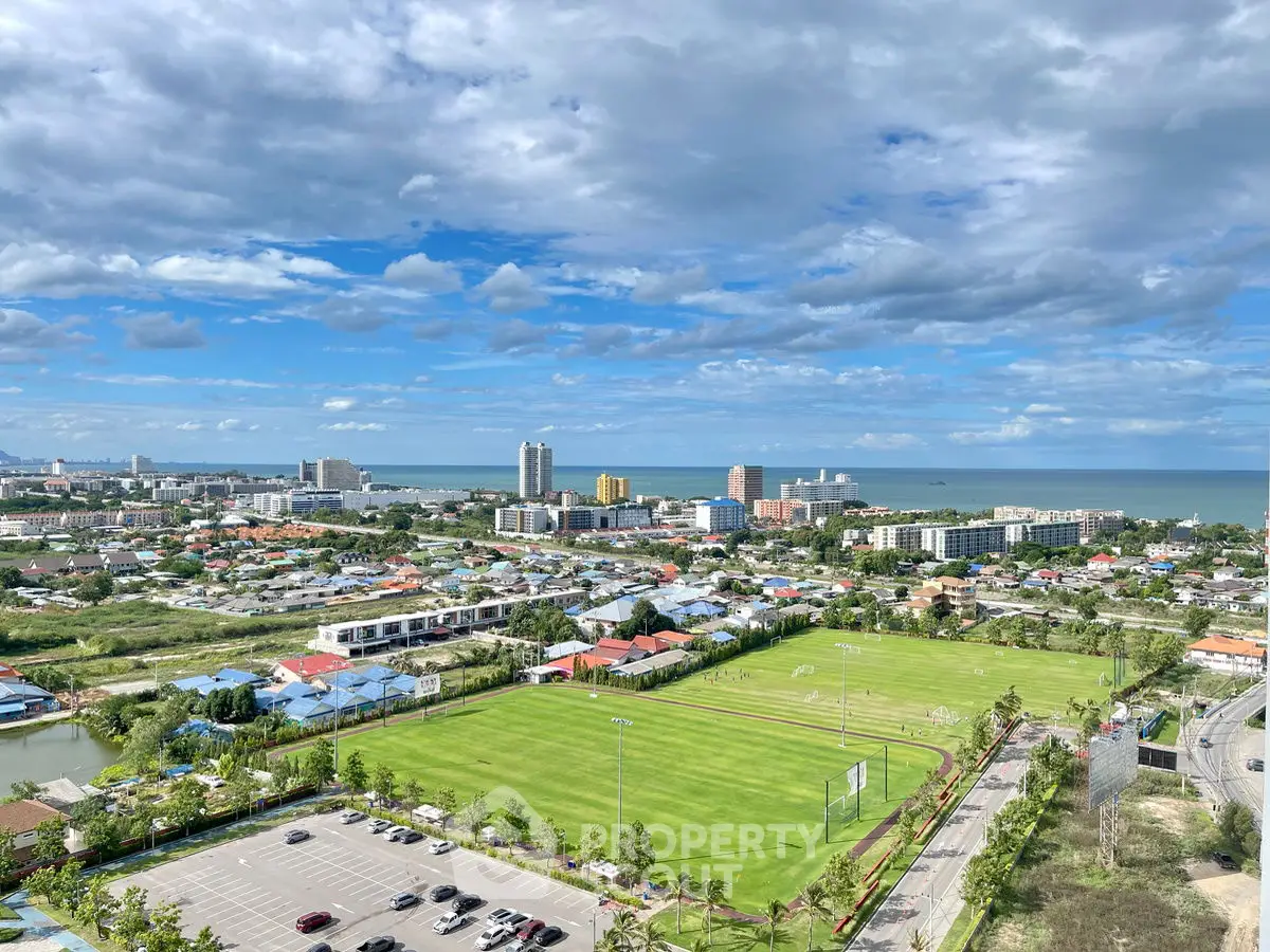 Stunning aerial view of coastal cityscape with lush green fields and ocean horizon.
