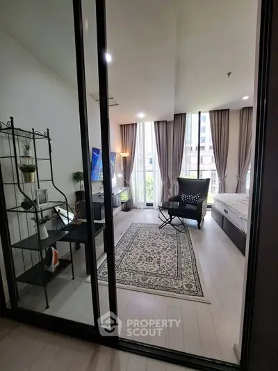 Modern bedroom with large windows, elegant decor, and cozy seating area in a stylish apartment.