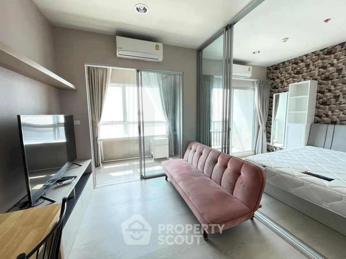 Modern apartment interior with stylish living room and bedroom, featuring a pink sofa and large windows.